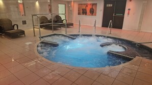 Una bañera de hidromasaje con asientos alrededor, suelo de baldosas y techo con sección de vidrio.