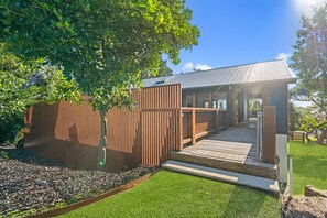 A modern building with a wooden exterior, a covered outdoor area, and a well-maintained lawn. - 6 Karboora Drive - Luxury holiday home with pool (Point Lookout)