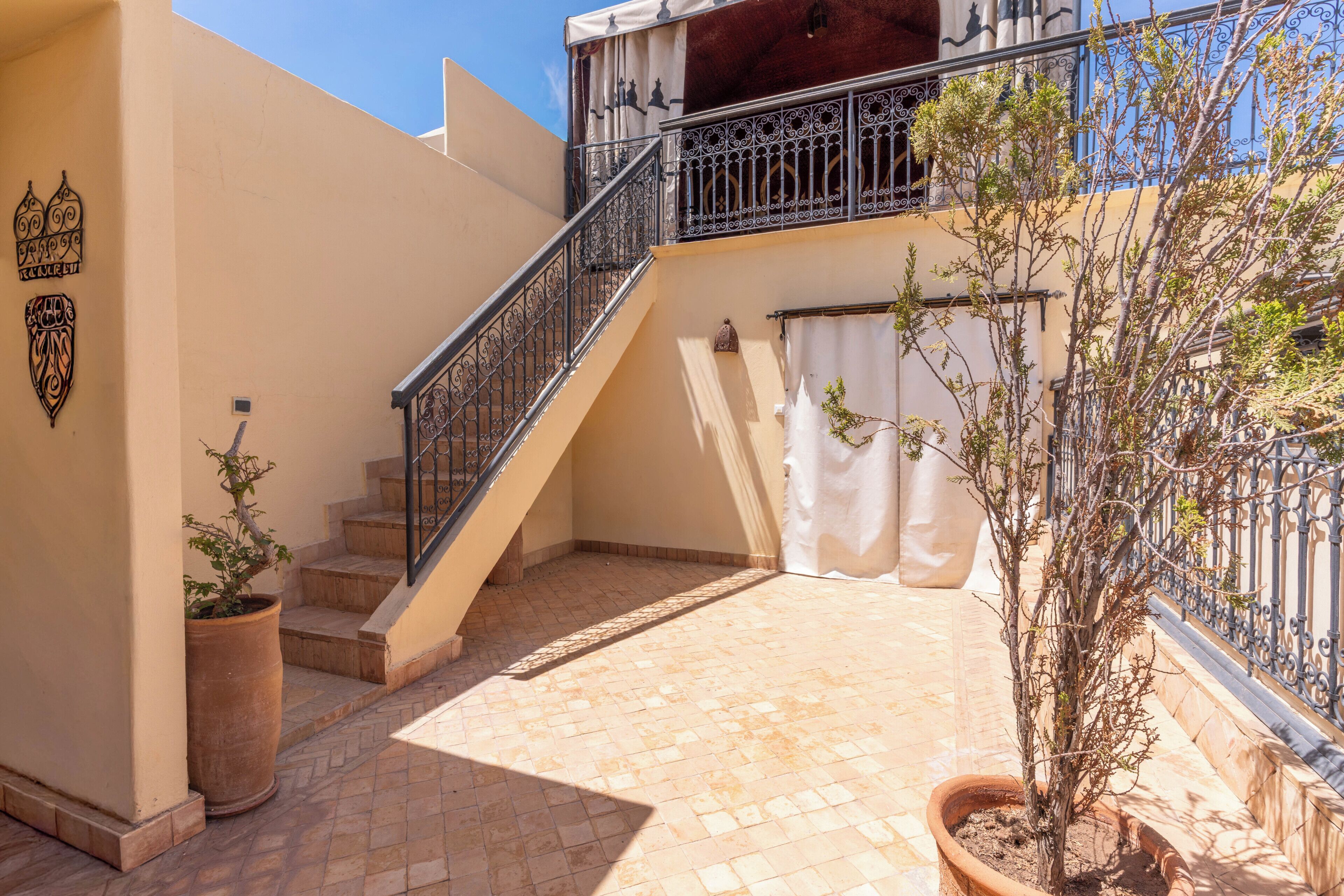 A building with a staircase, a balcony, and potted plants.