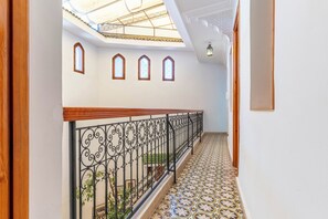 A corridor with a wooden railing, patterned floor tiles, and a skylight. - Riad Romouz Bab Ahmar (Marrakech)