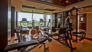 A gym with cardio equipment, weight machines, and benches. - Madin (Varanasi)