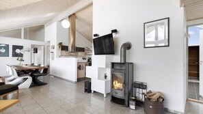 Ein modernes Interieur mit Kamin im Zentrum, einem Essbereich und einer Küche.