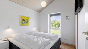 Ein Schlafzimmer mit einem Bett, Nachttischlampen, einem Fenster und einem Gemälde an der Wand.