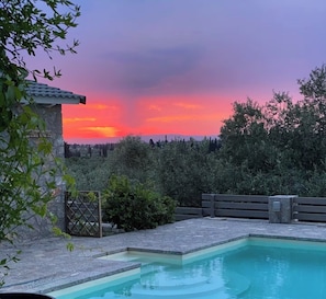 Ein Pool mit einer Steindeck, umgeben von Grünflächen und einer Steinstruktur.