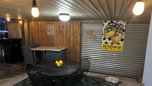 A covered outdoor seating area with a round table, chairs, and a 'Welcome' sign. - Cozy lower-level 1 bedroom studio in NOLA with Private Covered Outdoor Patio (New Orleans)