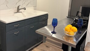 A modern kitchen with a marble backsplash, stainless steel appliances, and a wooden stool. - Cozy lower-level 1 bedroom studio in NOLA with Private Covered Outdoor Patio (New Orleans)