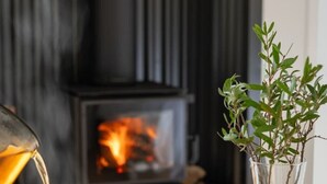 A cozy room with a fireplace, a cup of tea, biscuits, and a plant in a vase.