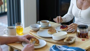 A breakfast setting with a table, cups, bowls, and a teapot.