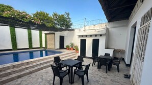 Un espace aménagé au bord de la piscine, comprenant une piscine, des sièges extérieurs et un patio couvert.