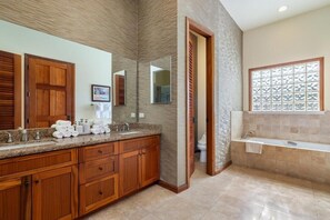Un bagno moderno con un mobile bagno in legno, uno specchio grande, una vasca e una finestra con un pannello decorativo.