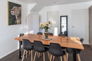 Ein Konferenzraum mit einem Holztisch, schwarzen Stühlen, einer Blumenvase und einem Leopardenbild an der Wand.