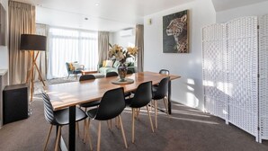 Uma área de jantar moderna com mesa de madeira, cadeiras pretas e um vaso de flores.
