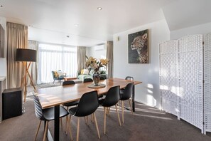 Ein moderner Essbereich mit einem Holztisch, schwarzen Stühlen und einer Blumenvase.