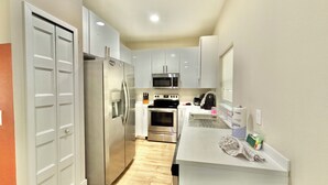 Una cocina compacta con refrigerador, microondas, horno y pileta.