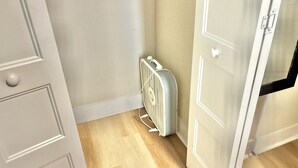 Una habitación con radiador, suelo de madera y puertas blancas.