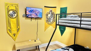 Una habitación con literas, un televisor de pantalla plana y tres carteles en la pared.