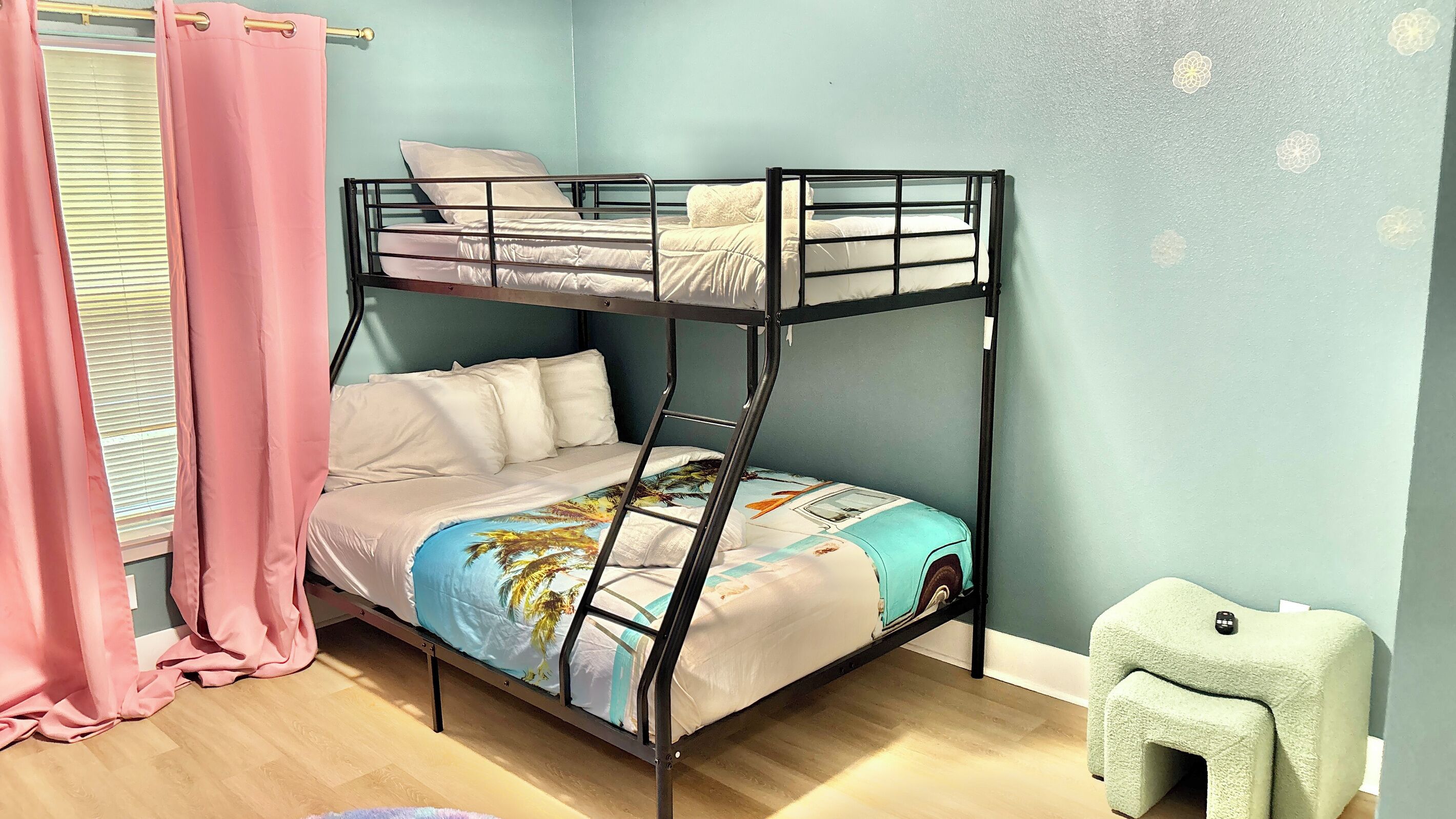 A bunk bed with a ladder, a small stool, and a window with curtains.