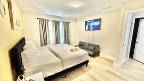 Ein Hotelzimmer mit Bett, einer Couch, einem Fernseher und einer Tür.