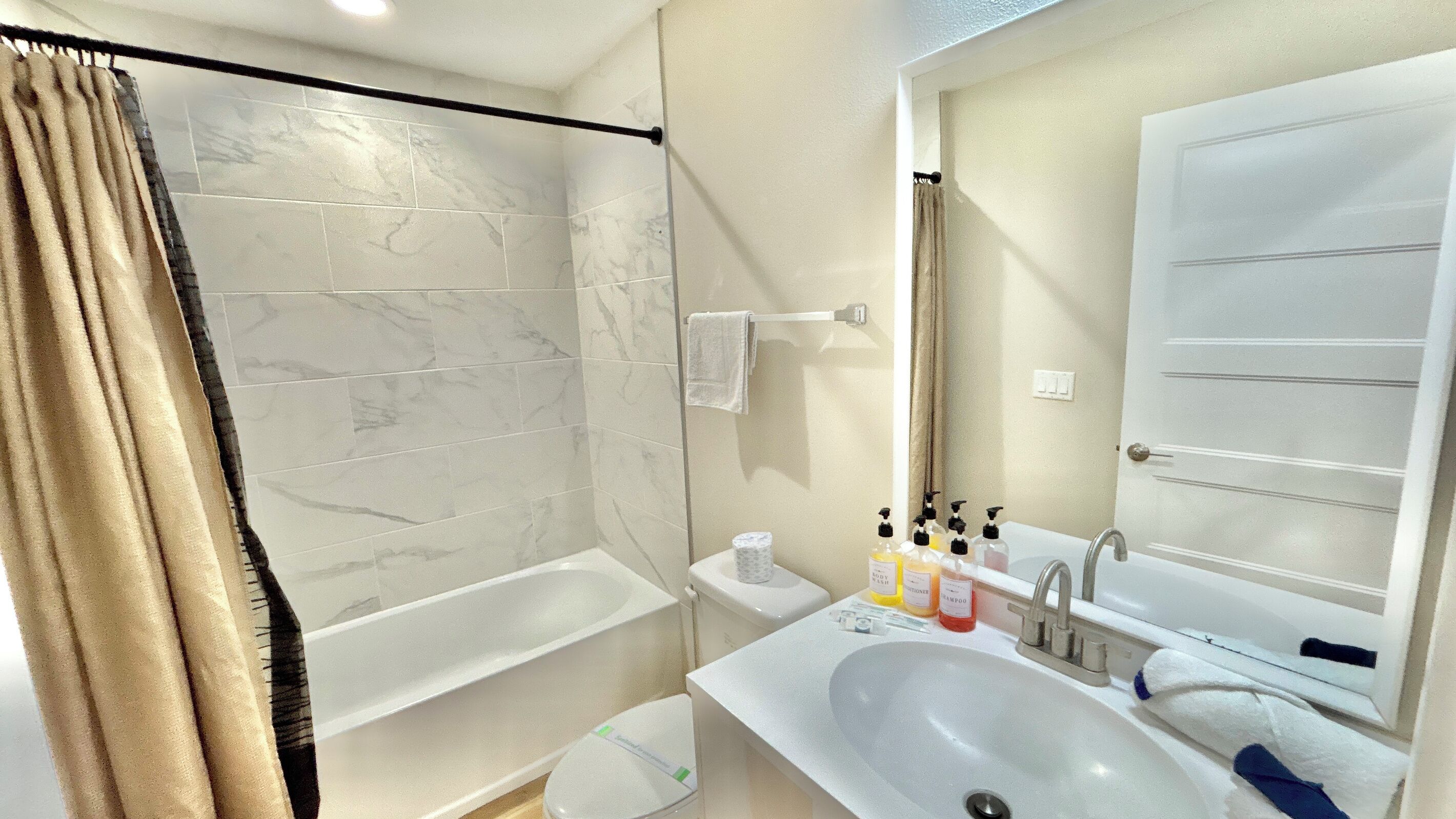 A bathroom with a bathtub, a shower, a sink, and a mirror.