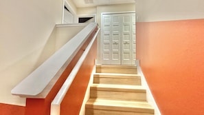 A staircase with a handrail leading to a white door. - Modern 4BR Townhome Near Disney | Sleeps 12 (Kissimmee)