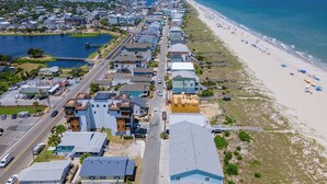 Luftaufnahme einer Küstenstadt mit Strand, Häusern und einer Straße.