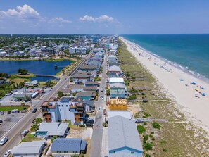Luftaufnahme einer Küstenstadt mit Strand, Häusern und einer Straße.
