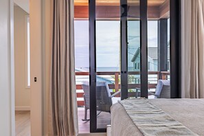 Ein Schlafzimmer mit einem großen Fenster, einem Bett und Blick auf einen Balkon mit Stühlen.