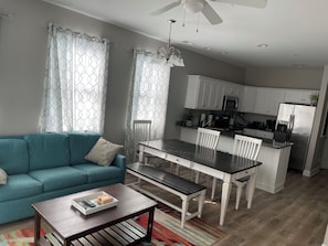 Ein modernes Wohnzimmer mit einer Couch, einem Couchtisch und einem Essbereich mit Stühlen und einem Tisch.