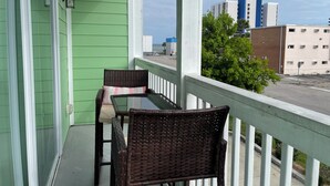 En balkon med fletmøbler og udsigt over bybilledet.