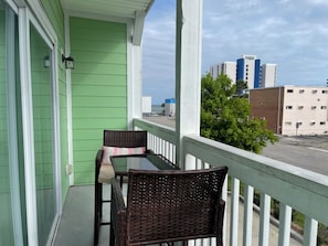 Ein Balkon mit Korbmöbeln und Blick auf eine Stadtlandschaft.