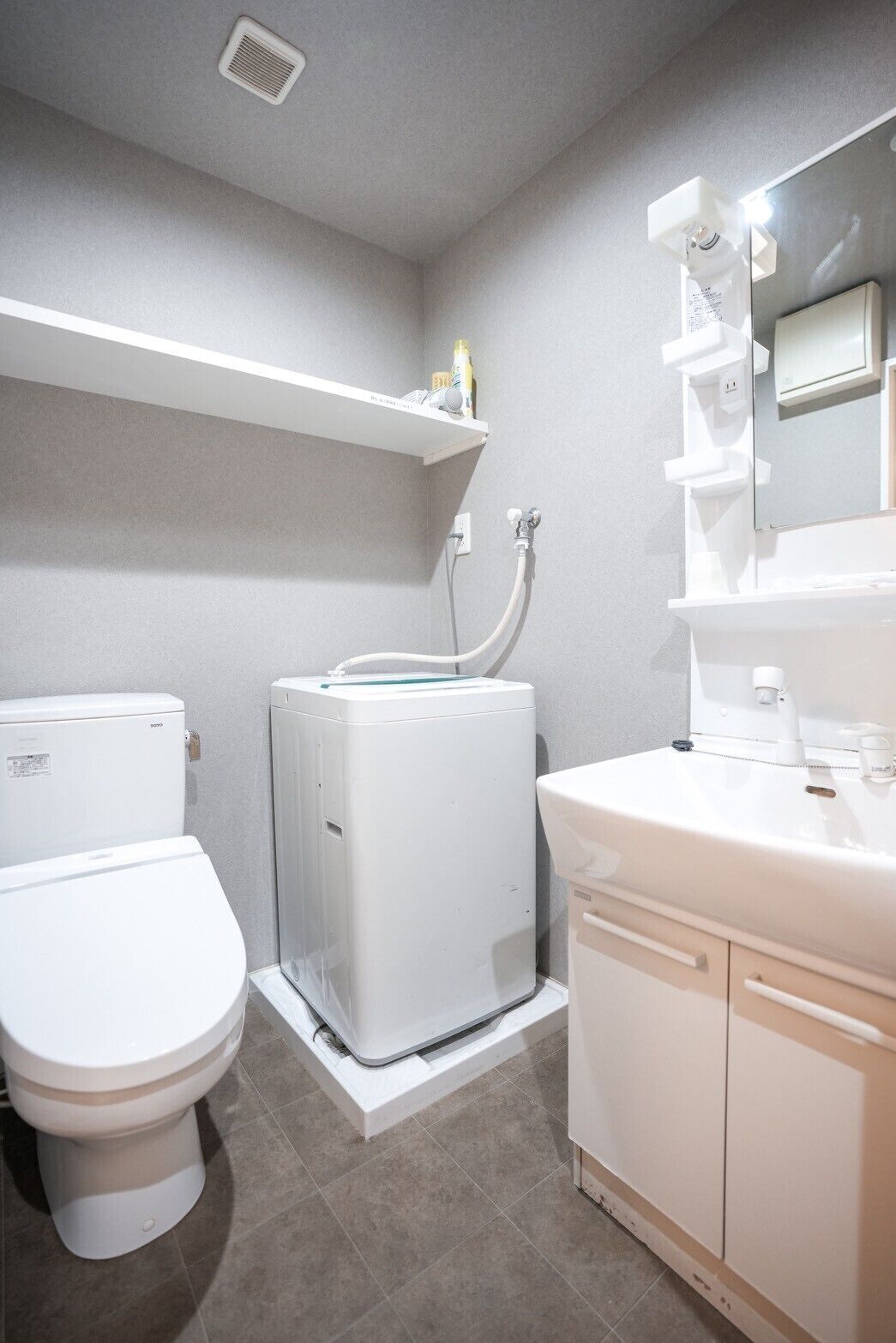 A bathroom with a toilet, a washing machine, and a sink.