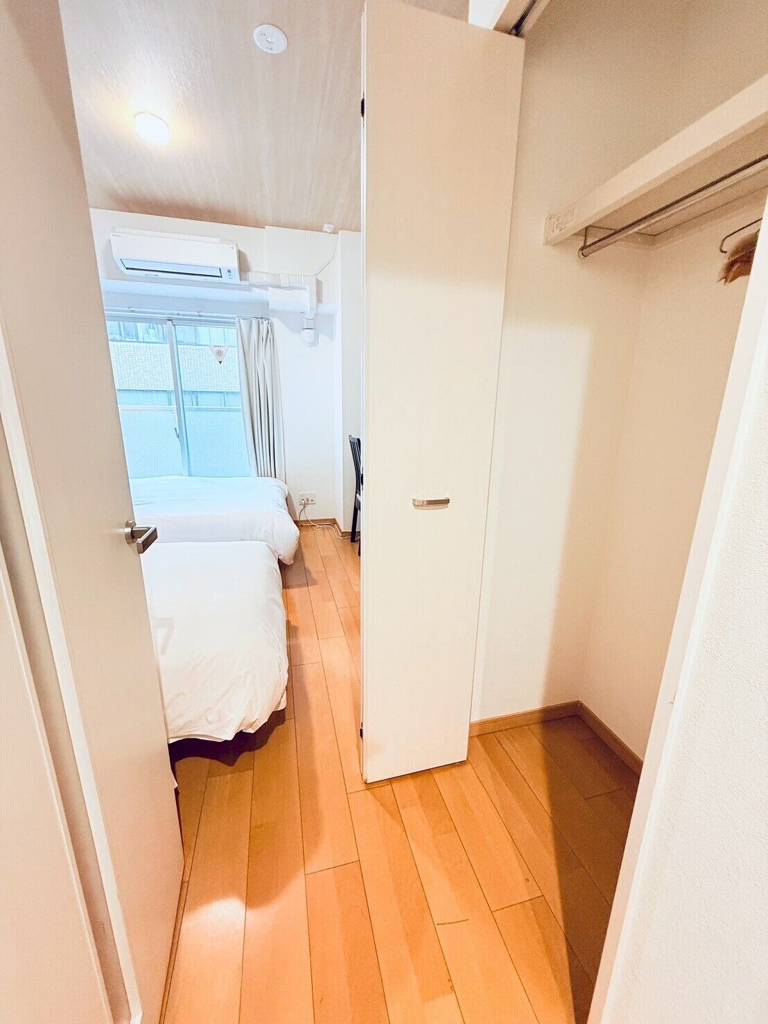 Habitación de hotel con cama, armario y ventana con cortinas.