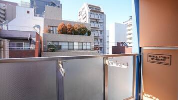 A view from a balcony with a metal railing, a building with a modern design, and a sign with Japanese text.