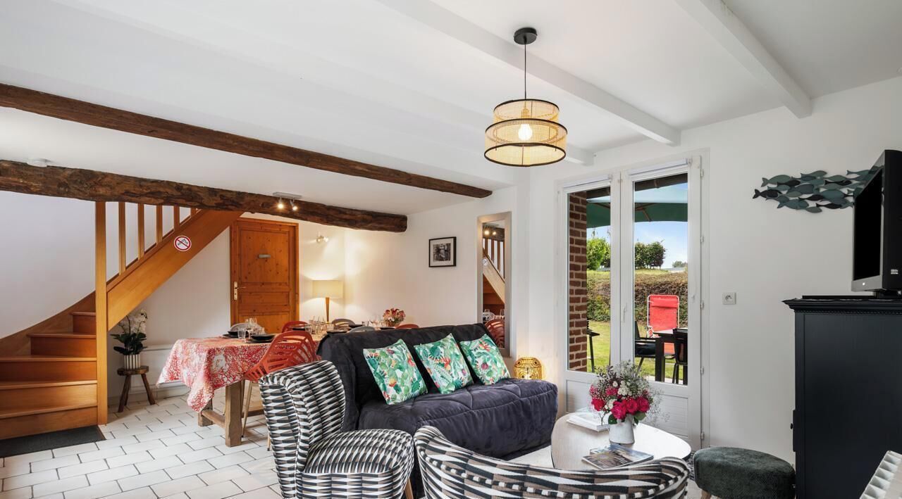 A cozy living room with a staircase, a dining area, and a TV.