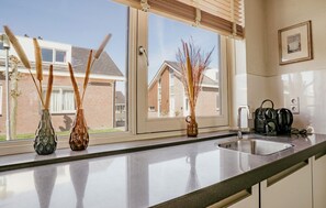 Eine Küche mit Fenster, Spüle und Wasserkocher auf der Arbeitsfläche.