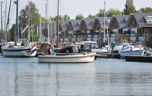 Eine Marina mit vertäuten Booten, eine Häuserreihe mit Satteldächern und ein klarer Himmel.