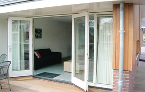 Ein Zimmer mit einer Schiebetür und Zugang zu einem Außenbereich, einem schwarzen Sofa und einem kleinen Tisch.
