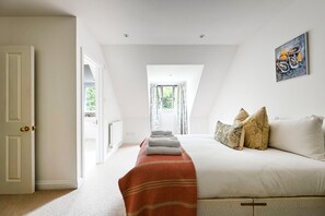 A bedroom with a bed, pillows, a radiator, a window, and a painting. - GuestReady - Modern Retreat with Classic Charm (London)