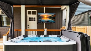 Een hottub met een houten terras, een deur en een schilderij van een ondergaande zon.