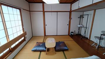 A traditional Japanese room with tatami flooring, a low table, cushions, and a sliding door.