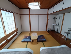 Una habitación japonesa tradicional con suelo de tatami, una mesa baja, cojines y un puertas correderas.