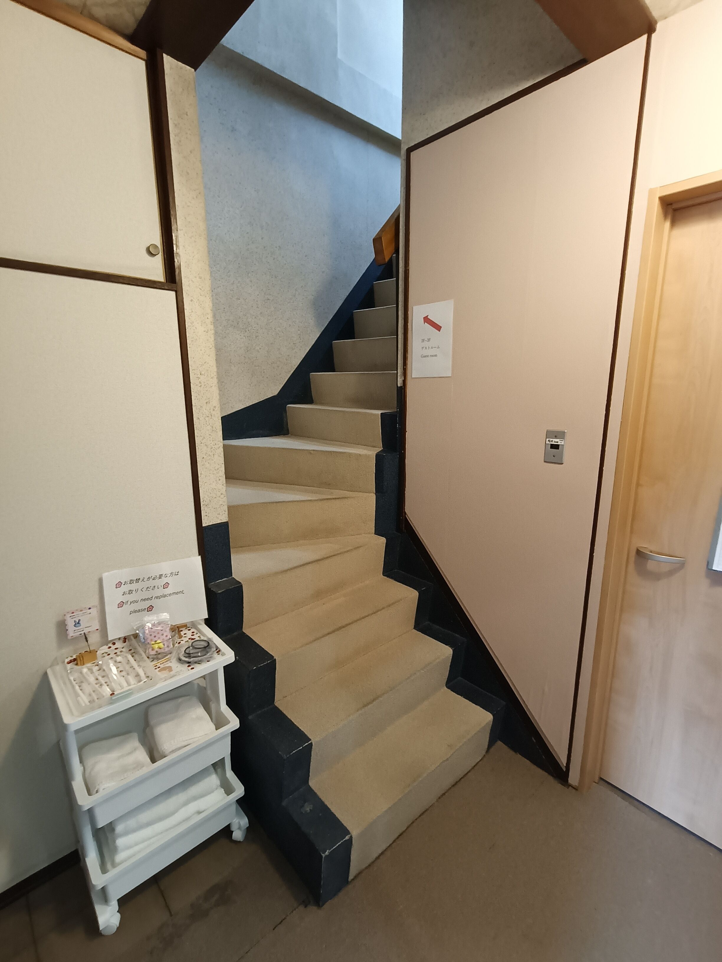 A staircase with beige steps, a white wall with a sign, and a door with a handle.