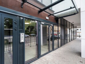 Une entrée moderne avec des portes en verre, une structure métallique et un trottoir dallé.