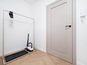 Une pièce avec une porte, un aspirateur et un petit tapis sur le sol.