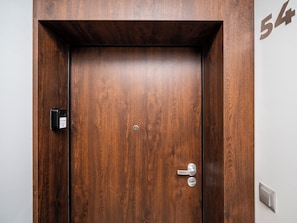 A wooden door with a numeric plaque, a doorbell, and a door handle. - Targowa Elegant Apartment (Łódź)