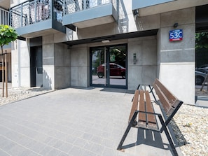 A building entrance with a bench, a car parked outside, and a sign indicating the address. - Targowa Elegant Apartment (Łódź)