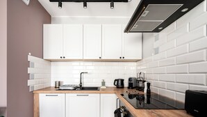 Una cocina moderna con armarios blancos, encimera de madera, estufa negra y cafetera.
