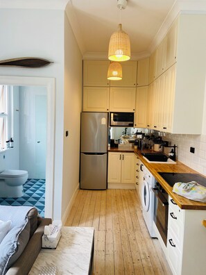 Eine kleine Küche mit Kühlschrank, Mikrowelle, Spüle und Holz Arbeitsplatte.