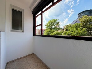 Ein Eckzimmer mit Fenster, Heizkörper und Fliesenboden.