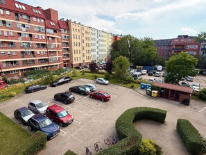 Ein mehrstöckiges Wohngebäude mit Parkplatz, Grünflächen und einer kleinen Struktur mit Dach.